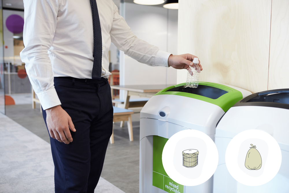 Employee throwing an empty bottle into a garbage bin in an office environment as part of waste management solutions